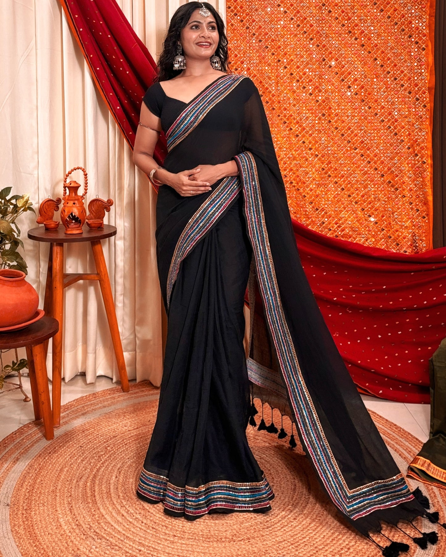 Woman in a black mulmul cotton saree with sequins embellished border - festive saree