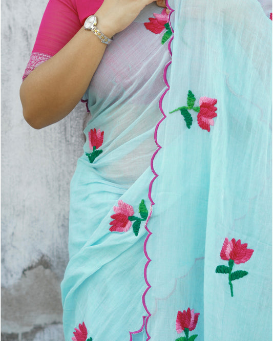 Cyan blue mulmul cotton saree with lotus embroidery, soft airy elegance for summer styling and festive moments.
