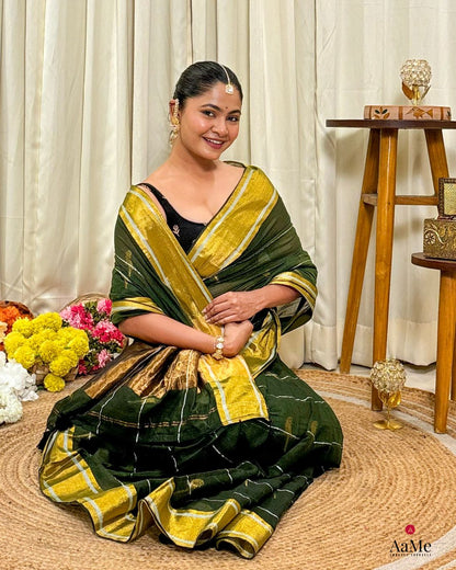 Woman in a handcrafted green mulmul cotton saree sitting on the floor with flowers 