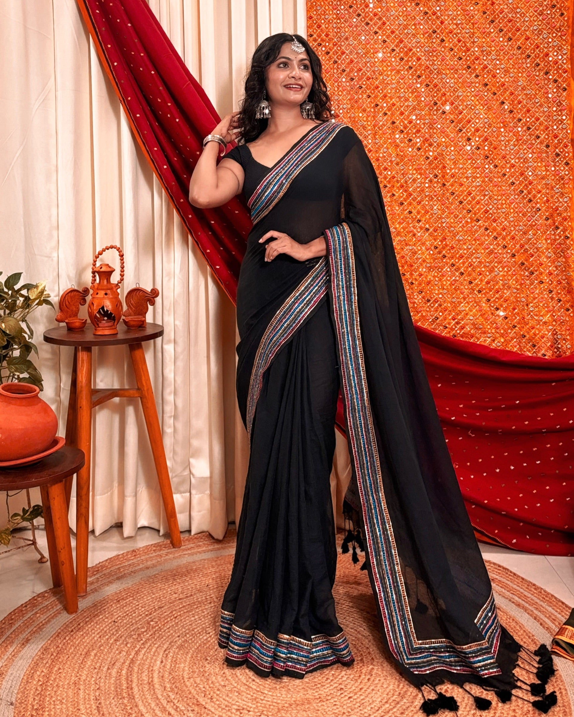 Woman in a black mulmul cotton saree with sequins embellished border - festive saree