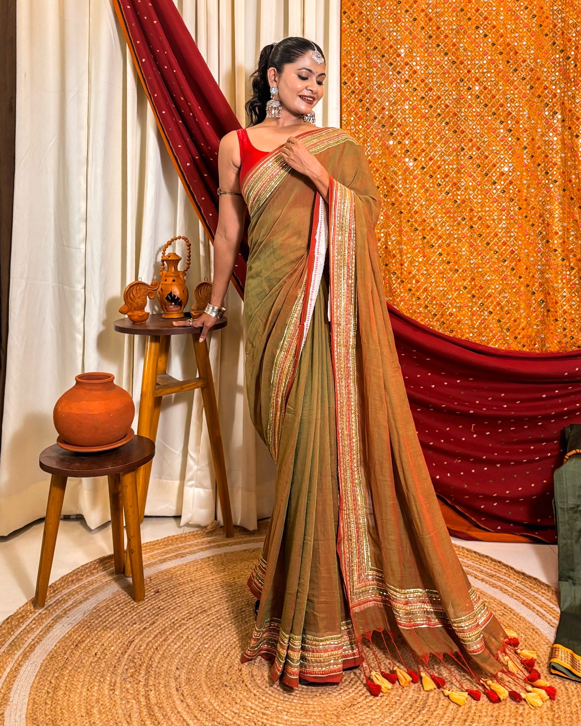 Woman in a dual tone green and red mulmul cotton saree with sequins embellished border - festive saree