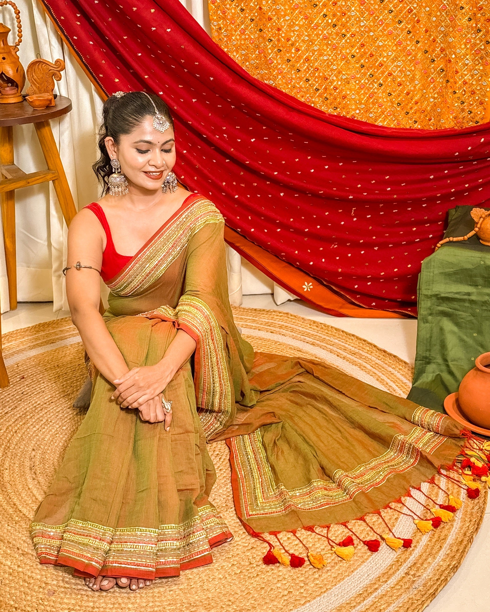 Woman in a dual tone green and red mulmul cotton saree with sequins embellished border - festive saree