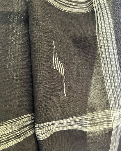 Close-up of a dark fabric with white embroidery and patterns