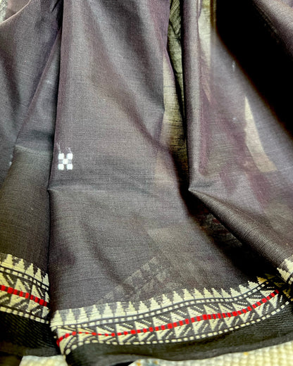 Close-up of a dark khadi cotton saree with intricate patterns and a brand logo.