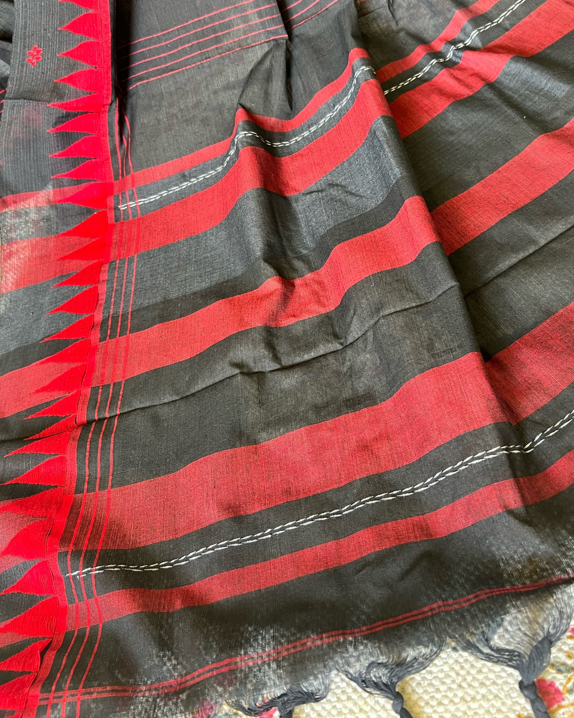 Close-up of a black and red striped khadi cotton saree with intricate patterns.