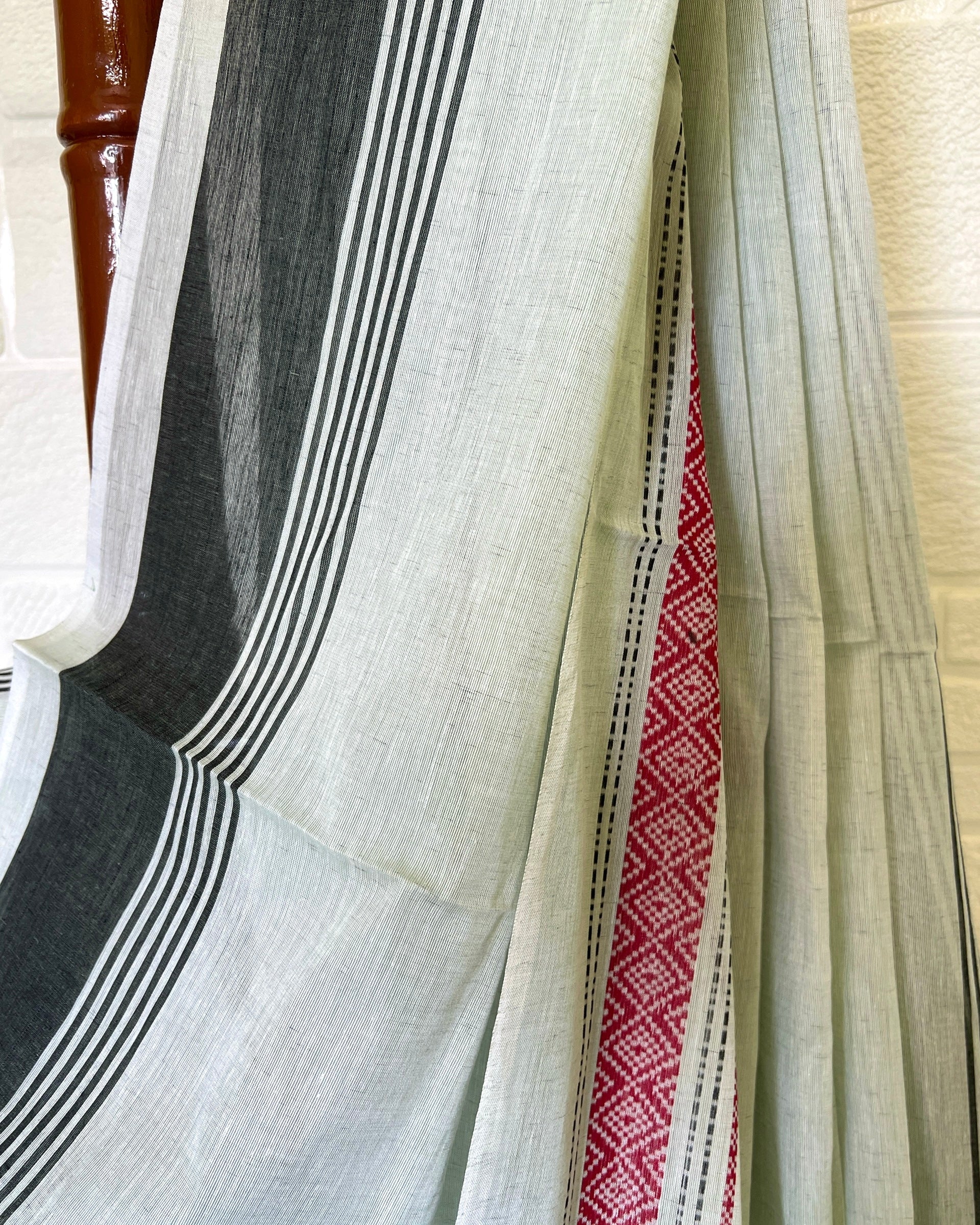 Khadi cotton saree with black, white, and red stripes on a wooden surface