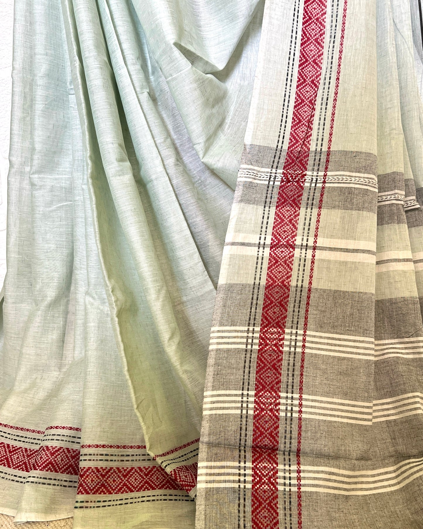 Light khadi cotton saree with red and white geometric patterns on a plain background