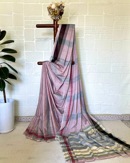 Pink and gray khadi cotton saree with a plant and white wall in the background