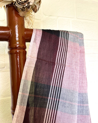 Pink khadi cotton saree draped over a wooden chair with a neutral background
