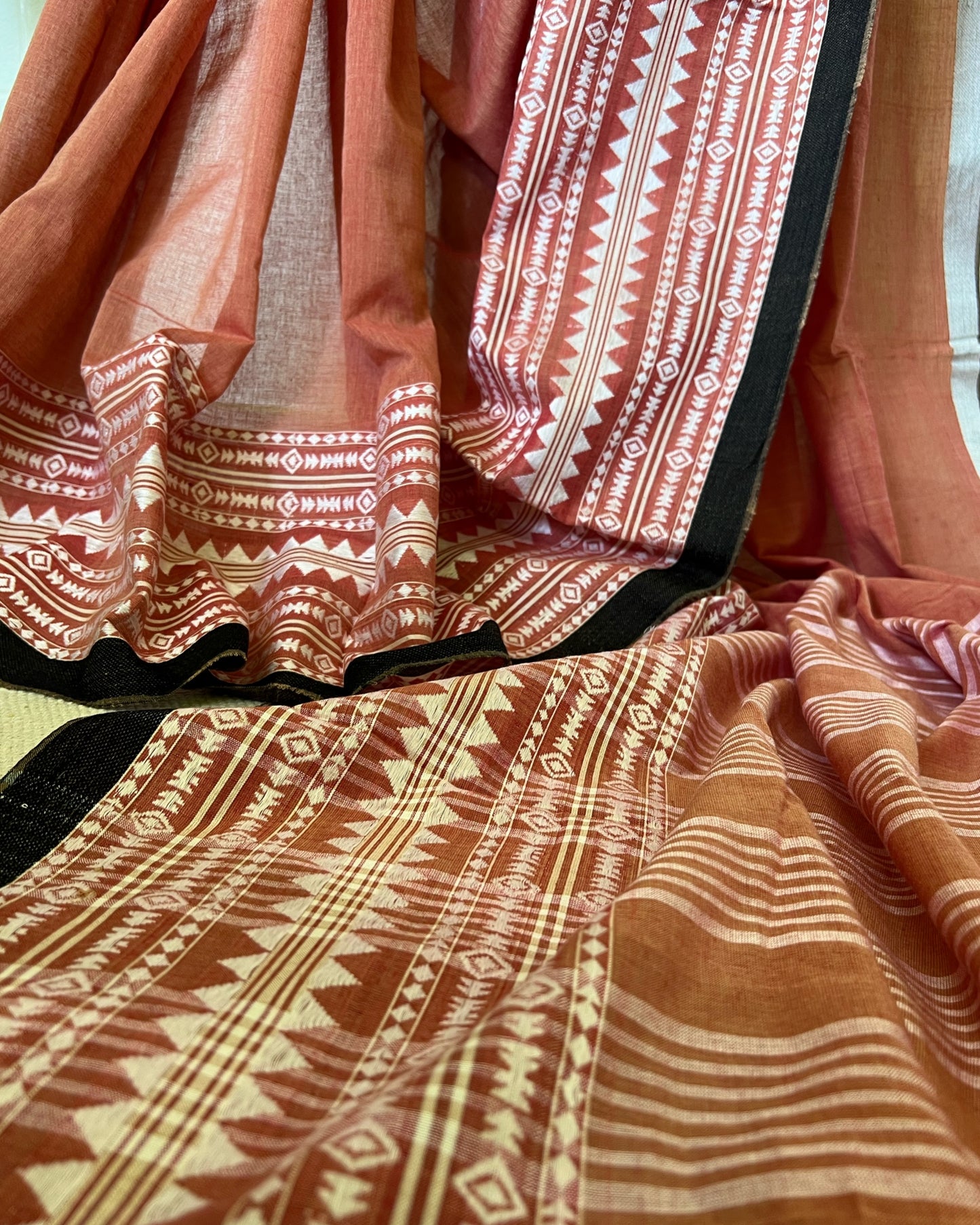 Close-up of khadi cotton saree with tribal designs in red and brown.