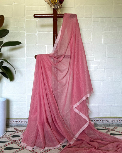 Pink handloom cotton saree by Shopaame draped over a chair against a white tiled wall.