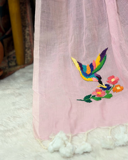 Pink mulmul cotton saree by Shopaame with colorful embroidery of a bird and flowers on a white surface.