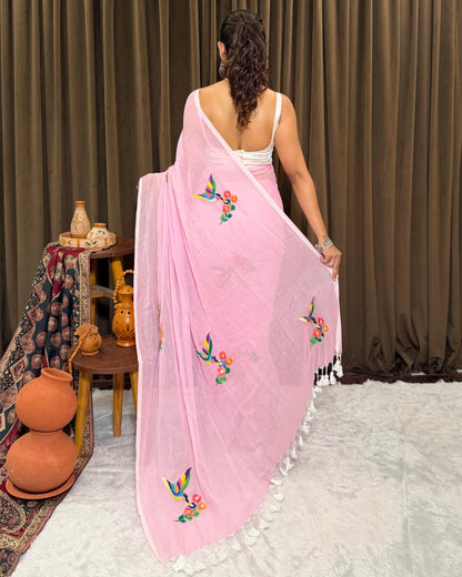 Woman wearing a pink mulmul cotton  Shopaame saree with floral embroidery in a room setting.